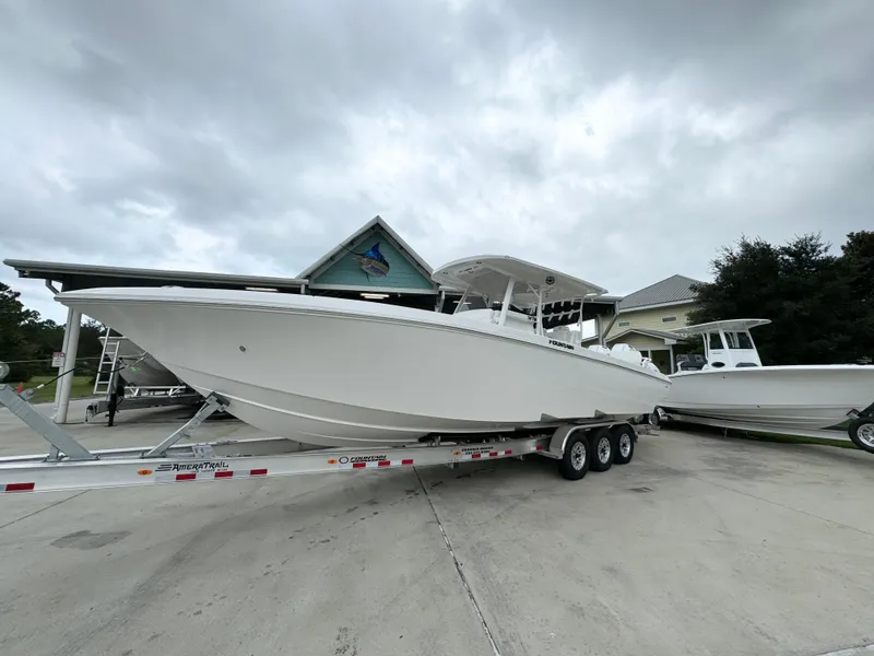 Slide: The Image of 2025 Fountain 34TE boat on trailer, parked outdoors under cloudy sky. - 3
