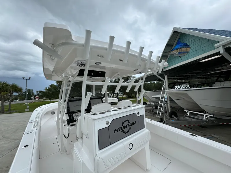 Slide: The Image of 2025 Fountain 34TE boat with T-top, docked near a boathouse under cloudy skies. - 32
