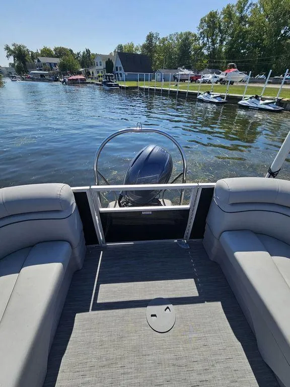 Slide: The Image of 2023 Bennington 24 SSR pontoon boat on a serene lake with scenic shoreline views. - 11