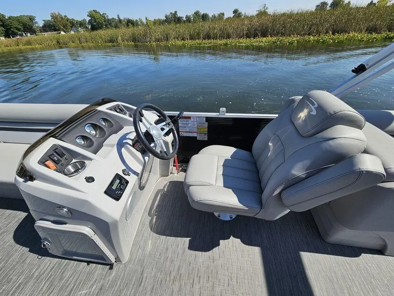 Slide: The Image of 2023 Bennington 24 SSR boat interior with steering console and plush seating by the water. - 7