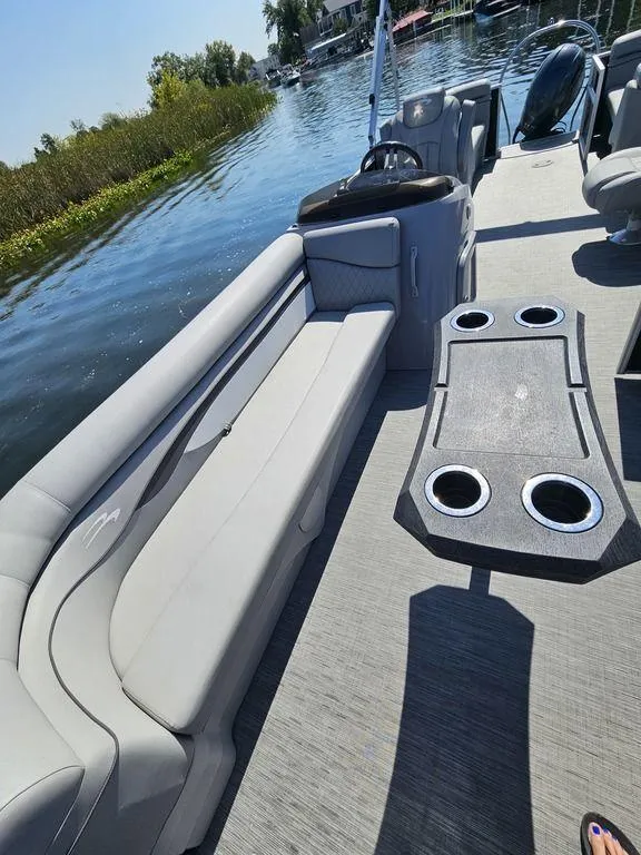 Slide: The Image of 2023 Bennington 24 SSR pontoon boat with spacious seating and cup holders on a sunny lake. - 8