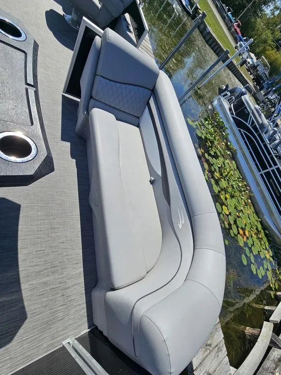 Slide: The Image of 2023 Bennington 24 SSR boat with sleek gray seating by a lily pad-covered dock. - 9