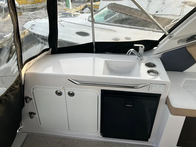 Slide: The Image of 2014 Four Winns Vista 275 boat interior with sink, mini fridge, and storage cabinets. - 17
