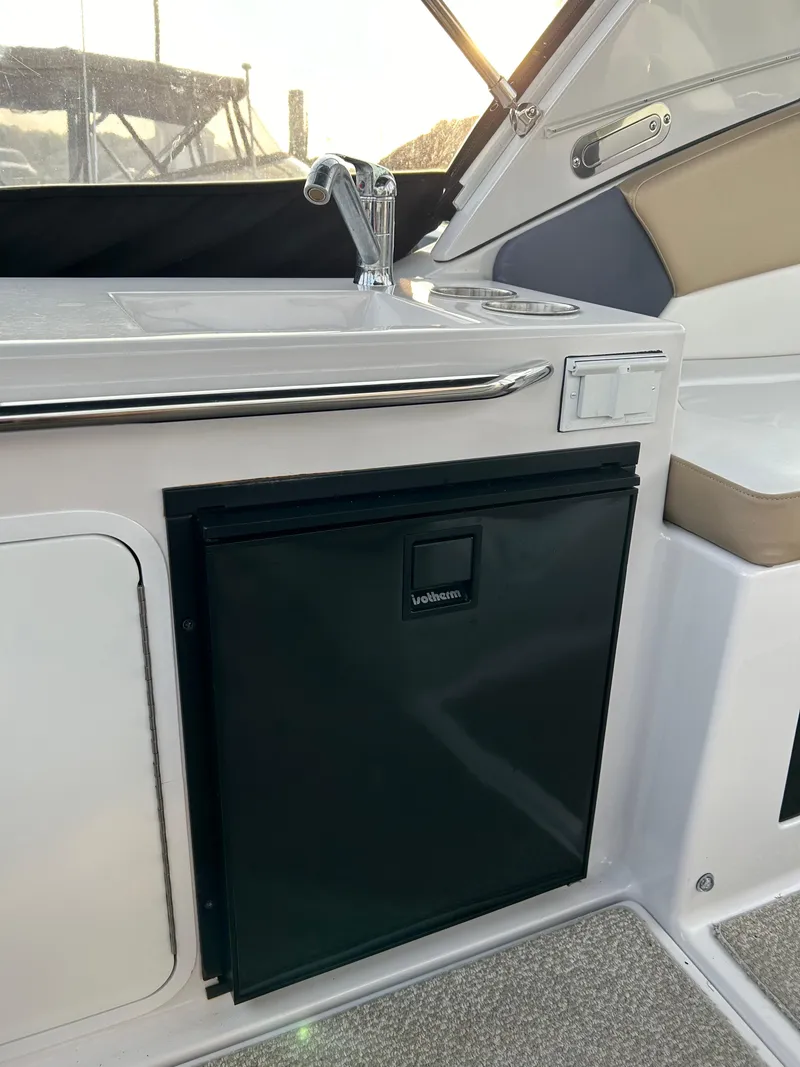 Slide: The Image of 2014 Four Winns Vista 275 boat interior with a compact kitchenette and mini fridge. - 20