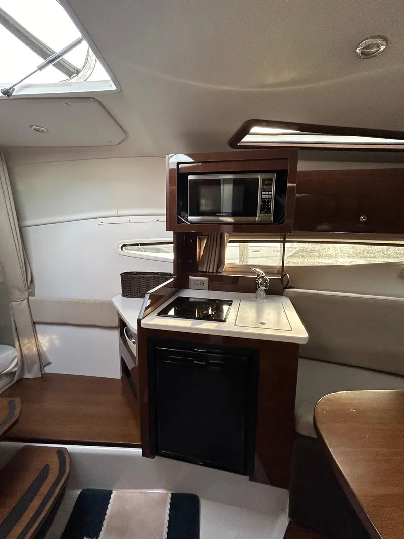 Slide: The Image of 2014 Four Winns Vista 275 interior with kitchenette, featuring microwave, sink, and compact fridge. - 6