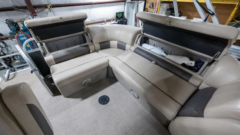 Slide: The Image of 2021 Sun Tracker Party Barge 20 DLX interior with beige seating and storage compartments. - 11