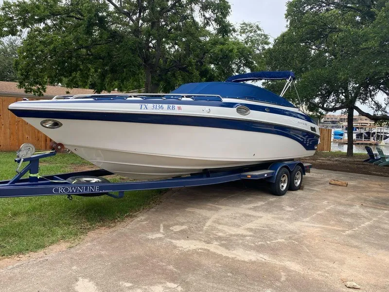 Slide: The Image of 2003 Crownline 270 BR boat on trailer, parked outdoors with trees in background. - 1