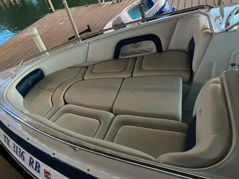 Slide: The Image of 2003 Crownline 270 BR boat interior with cushioned seating, docked by the water. - 2