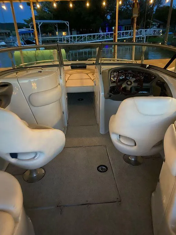 Slide: The Image of 2003 Crownline 270 BR boat interior with white seating and dashboard, docked at sunset. - 23