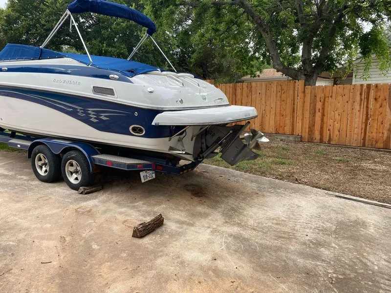 Slide: The Image of 2003 Crownline 270 BR boat on trailer, parked in driveway near wooden fence. - 26