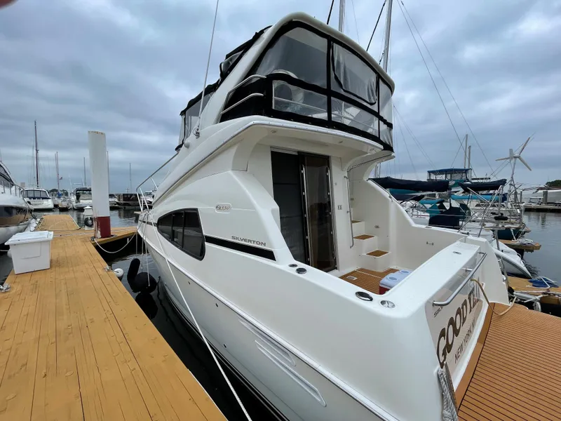 Slide: The Image of 2007 Silverton 330 Sport Bridge yacht docked at marina, showcasing sleek design and spacious deck. - 2