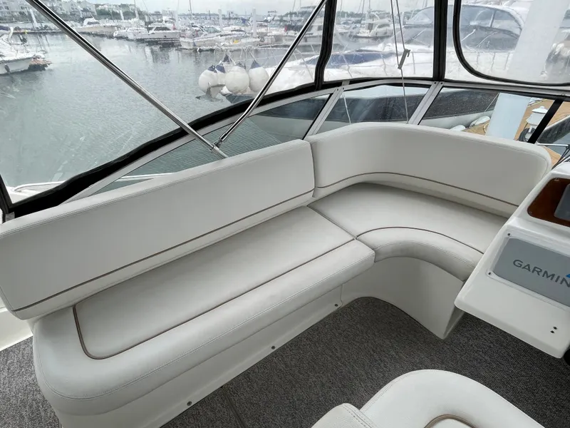 Slide: The Image of 2007 Silverton 330 Sport Bridge interior with white seating, overlooking marina. - 9