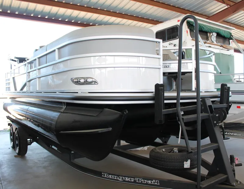 Slide: The Image of 2025 Ranger RP223FC pontoon boat on trailer in covered storage area. - 1