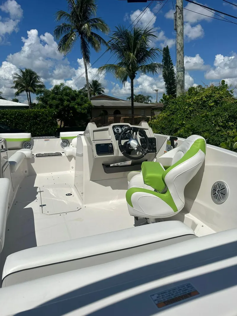 Slide: The Image of 2022 Starcraft SVX 191 OB boat interior with green and white seating, palm trees in background. - 21