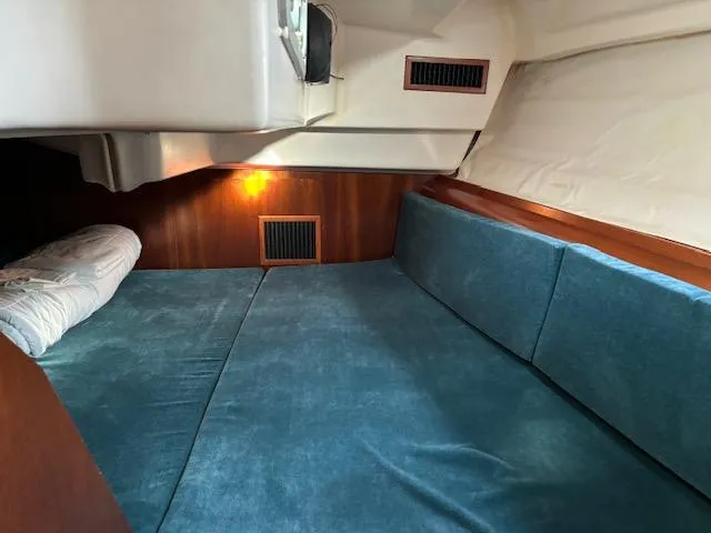 Slide: The Image of Cozy cabin interior of 1998 Beneteau 381 sailboat with blue cushions and wood paneling. - 43