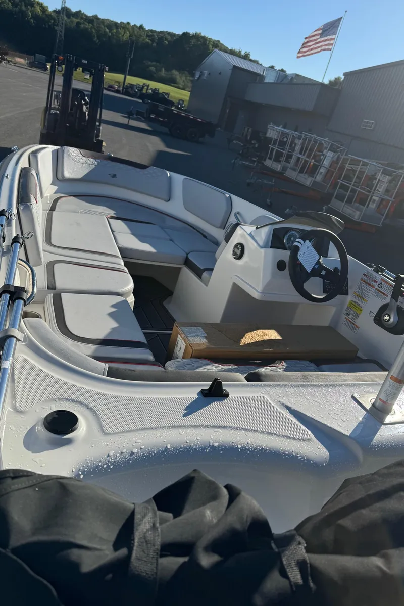 Slide: The Image of 2025 Bayliner 15E boat interior with seating and steering wheel, parked outdoors. - 7
