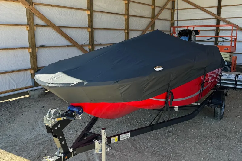 Slide: The Image of 2025 Bayliner 15E boat covered in storage, red hull, on trailer. - 8