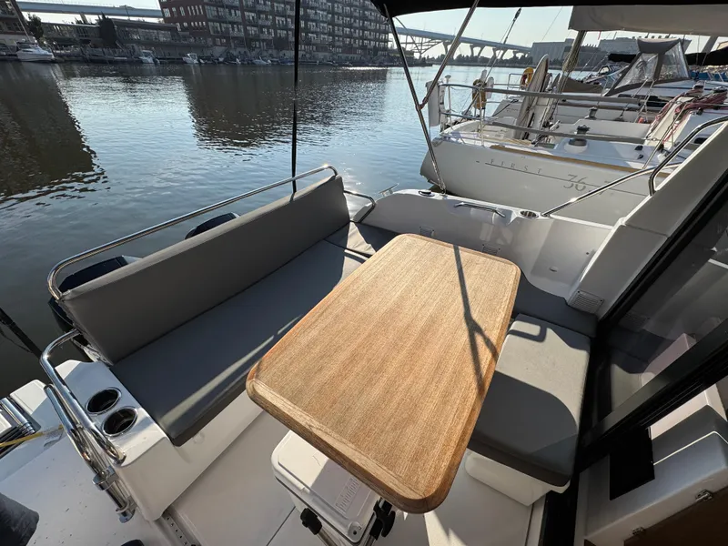 Slide: The Image of 2023 Beneteau Antares 9 boat interior with seating and wooden table by the water. - 22