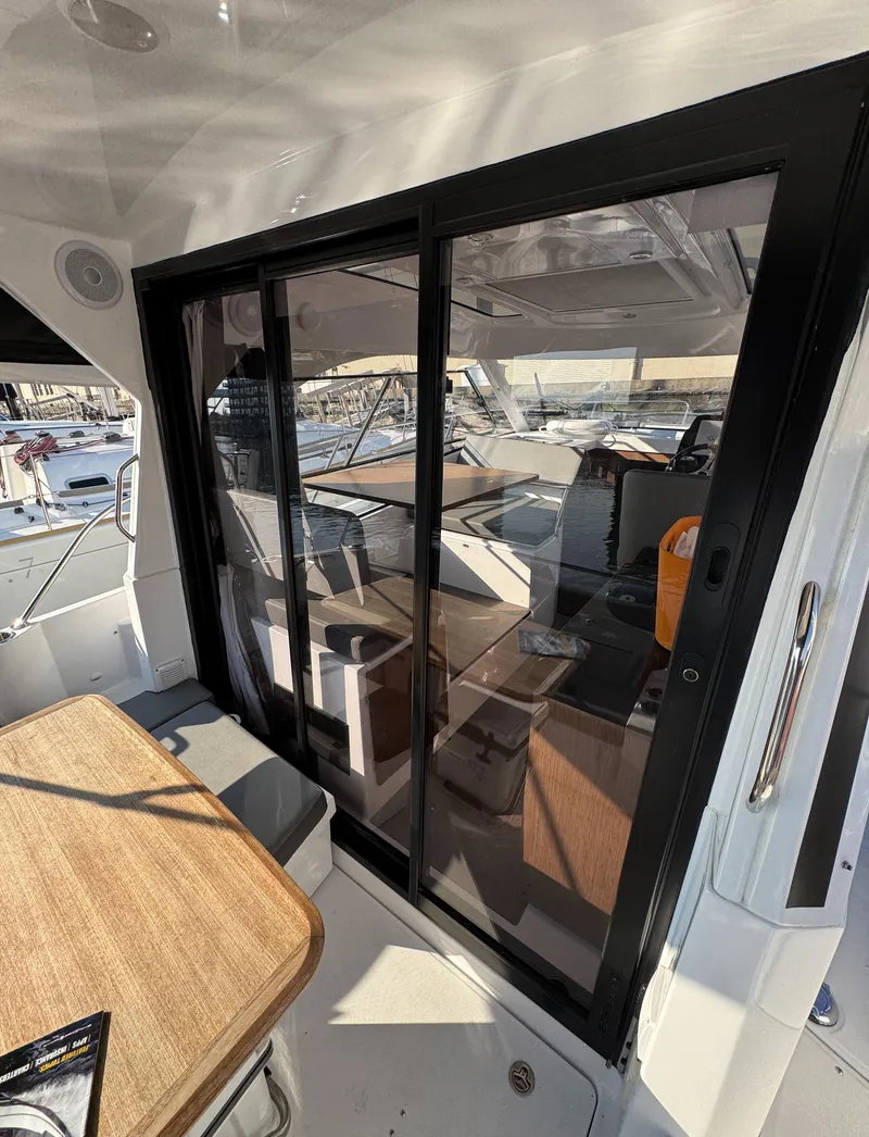 Slide: The Image of 2023 Beneteau Antares 9 interior view with sliding glass doors and wooden table. - 24