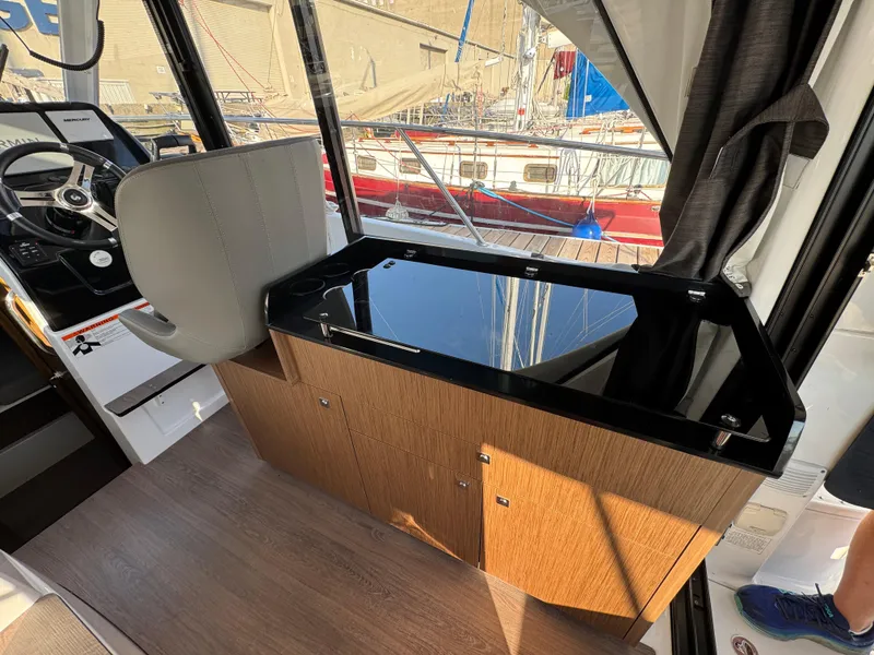 Slide: The Image of Interior of 2023 Beneteau Antares 9 boat with modern helm and wooden cabinetry. - 26