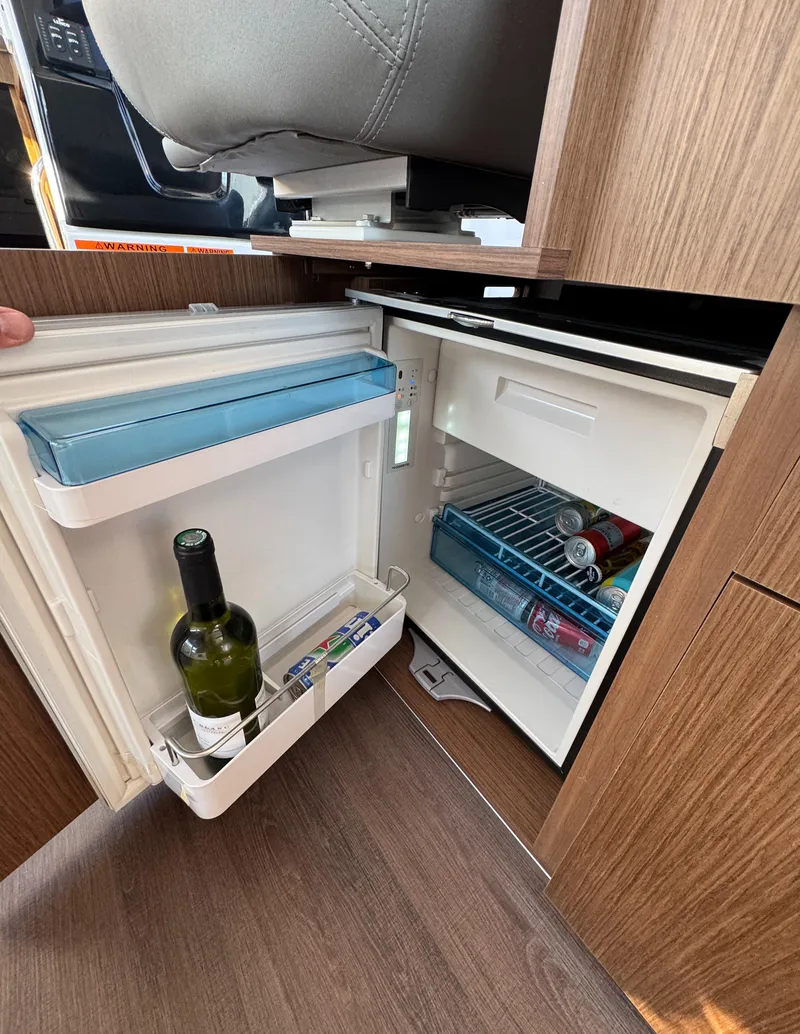 Slide: The Image of Compact fridge in 2023 Beneteau Antares 9 boat interior, stocked with drinks. - 29