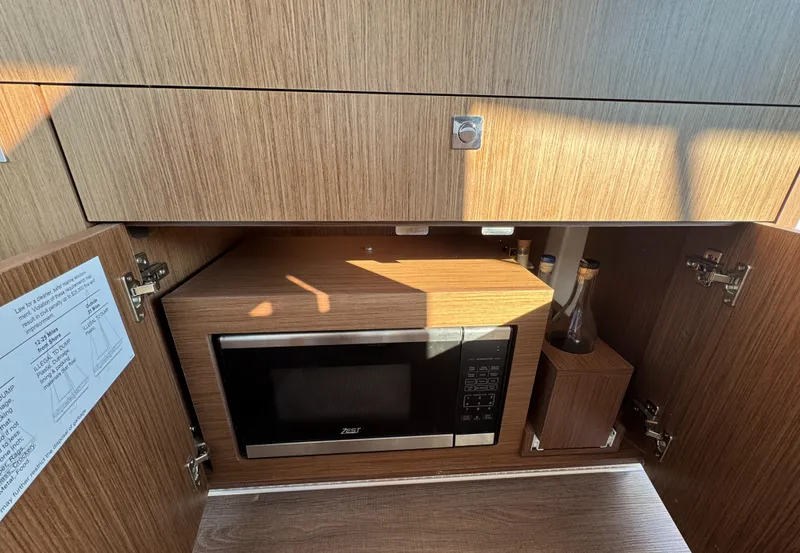 Slide: The Image of 2023 Beneteau Antares 9 interior with microwave and wooden cabinetry. - 30
