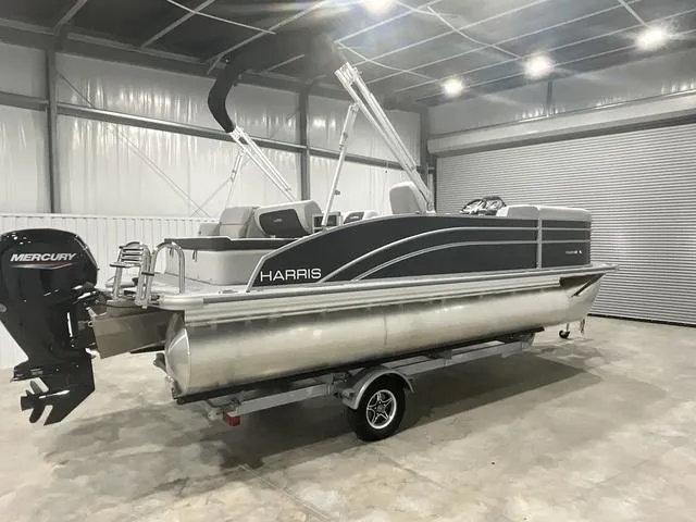 Slide: The Image of 2025 Harris Cruiser 210 SL pontoon boat in a garage with Mercury outboard motor. - 4