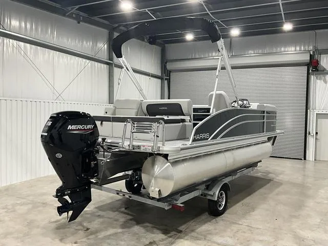 Slide: The Image of 2025 Harris Cruiser 210 SL pontoon boat in a garage, featuring a Mercury outboard motor. - 7