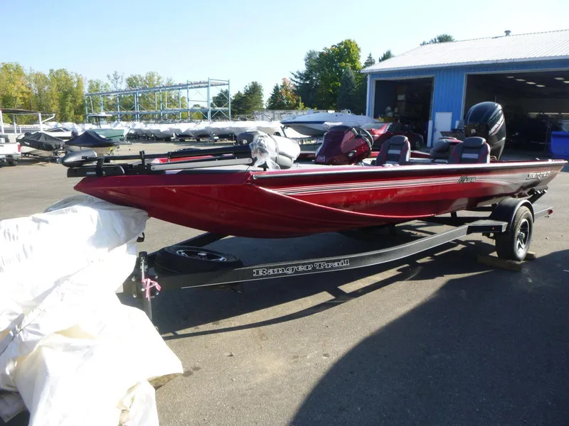 Slide: The Image of 2024 Ranger RT188 boat in red, parked on a trailer outside a blue building. - 3