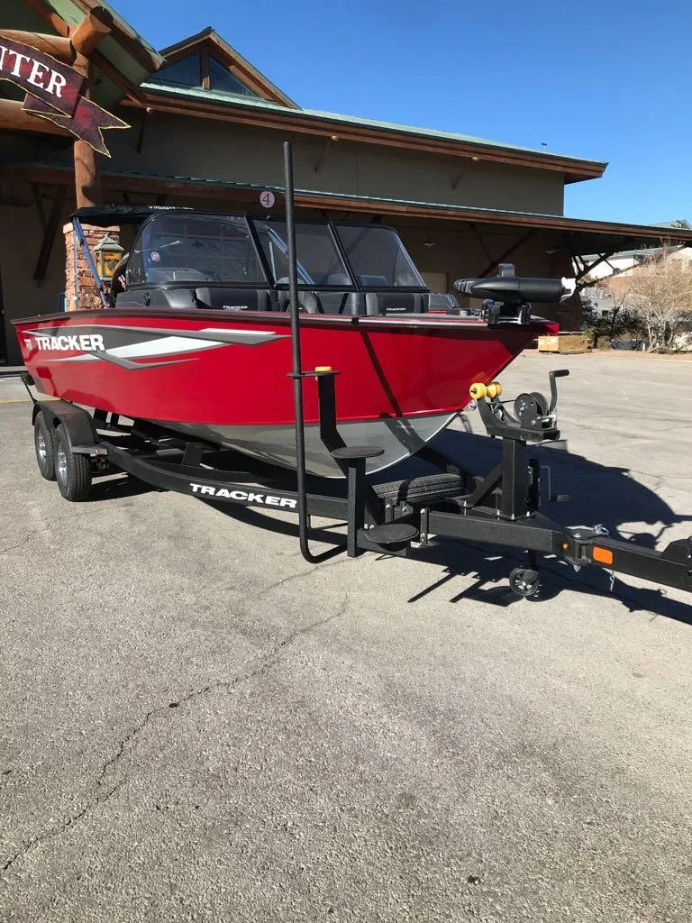 Slide: The Image of 2025 Tracker Targa V-18 Combo boat on trailer, red exterior, parked outdoors. - 11