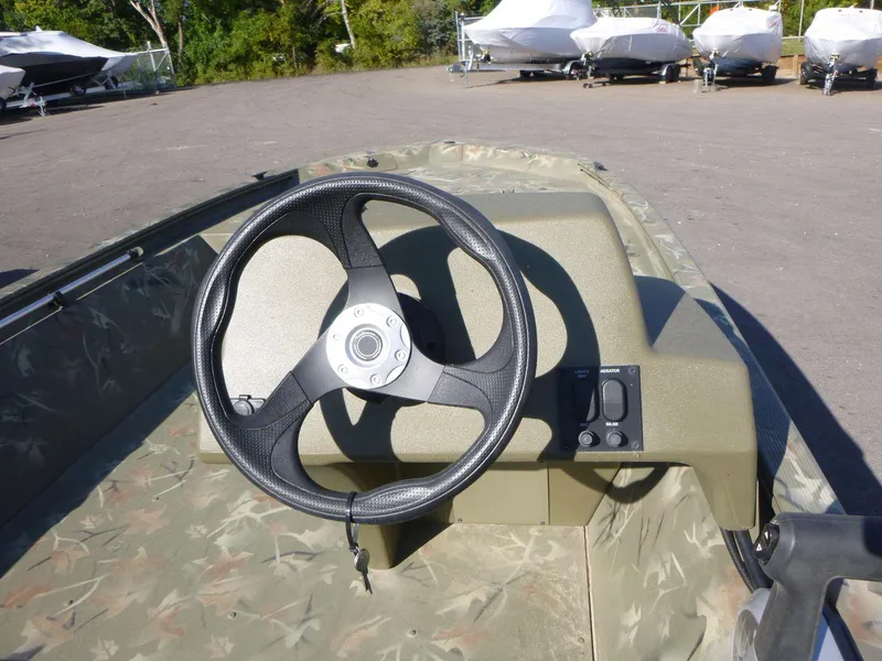 Slide: The Image of 2024 Tracker Grizzly 1648 SC boat steering wheel and console in outdoor setting. - 13