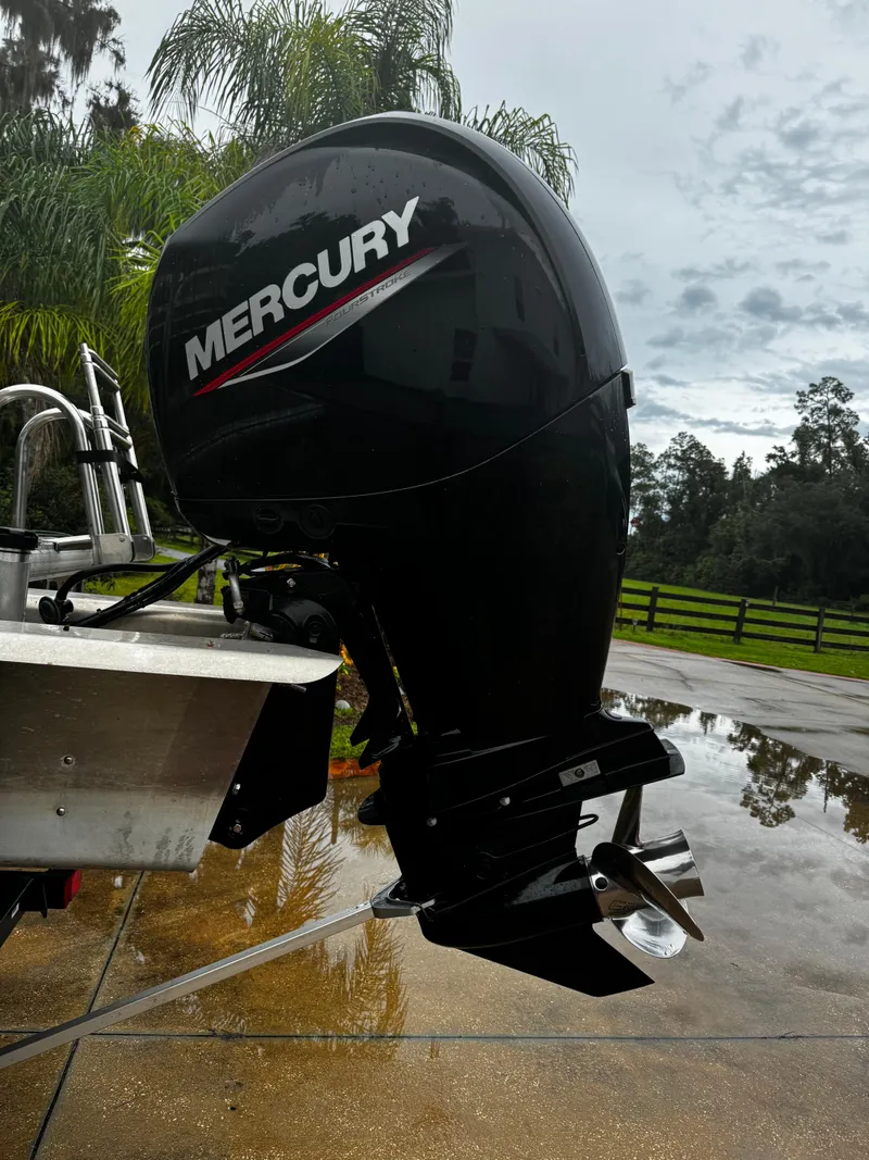Slide: The Image of Mercury outboard motor on 2023 Sun Tracker Party Barge 22 DLX, parked on wet pavement. - 20