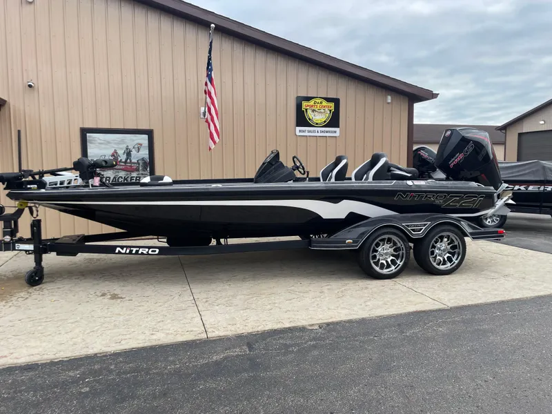 Slide: The Image of 2025 Nitro Z21 XL Pro boat on trailer, parked outside a building with American flag. - 2