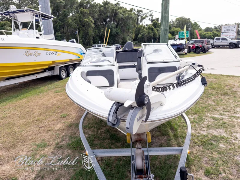 Slide: The Image of 2015 Caravelle 19 EBO boat on trailer, parked outdoors near other boats. - 2