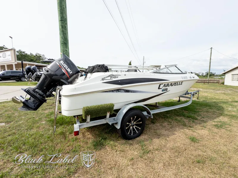 Slide: The Image of 2015 Caravelle 19 EBO boat on trailer with Suzuki outboard motor, parked on grass. - 4