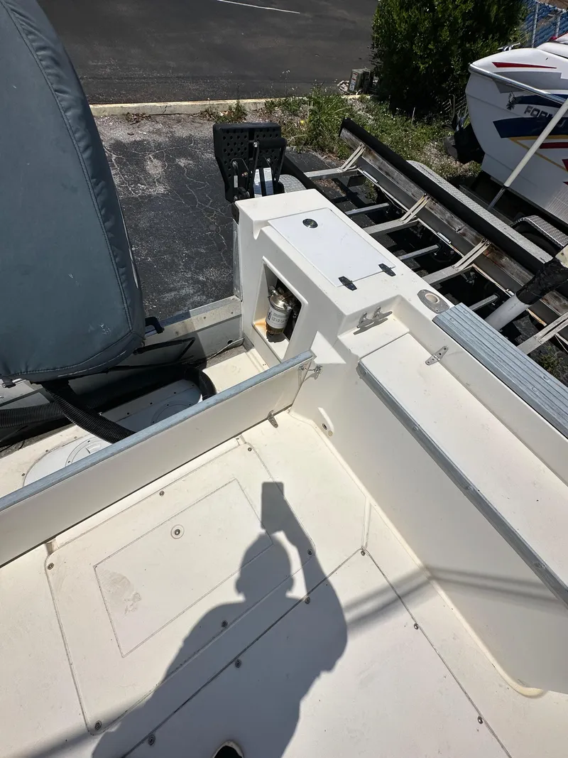 Slide: The Image of 1987 Mako 228 boat interior with shadow, docked near trailer. - 18