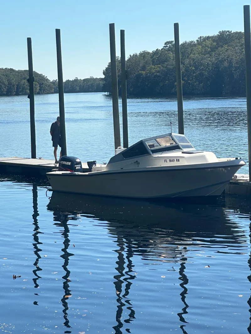 Slide: The Image of 1987 Mako 228 boat docked on a calm river with trees in the background. - 2