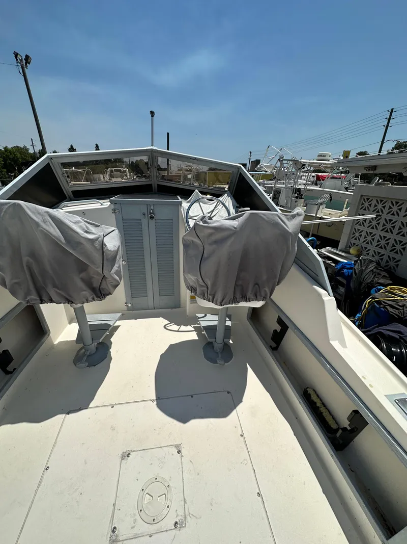 Slide: The Image of 1987 Mako 228 boat interior with covered seats and console under clear blue sky. - 26