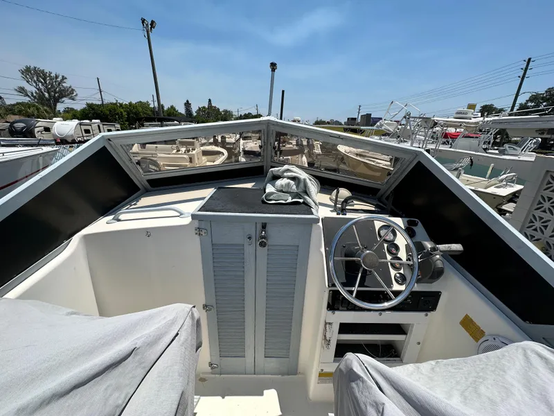 Slide: The Image of 1987 Mako 228 boat cockpit with steering wheel and controls, docked under clear sky. - 29