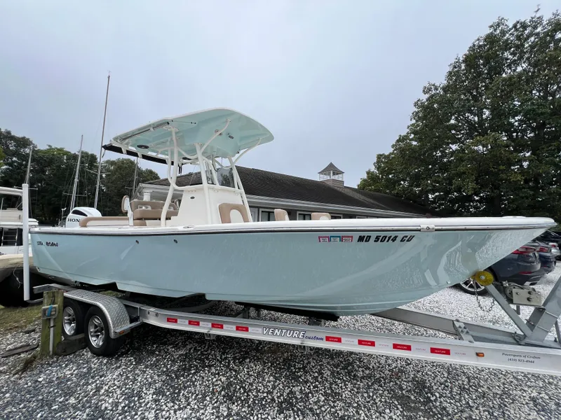 Slide: The Image of 2023 Sea Born LX24 Center Console boat on a trailer, parked outdoors. - 2