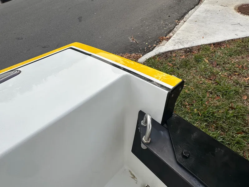 Slide: The Image of 1990 Superboat 21 rear corner detail with yellow trim, parked on grass by the road. - 17