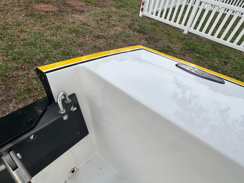 Slide: The Image of 1990 Superboat 21 boat detail, white hull with yellow trim, grassy background. - 18