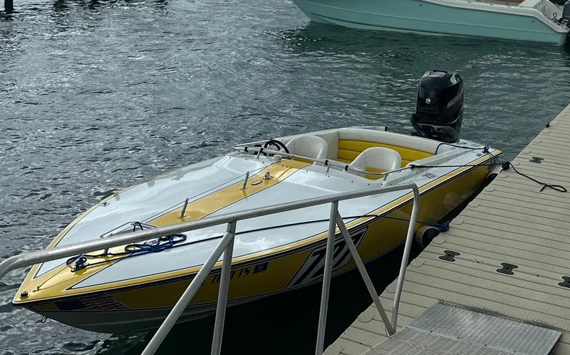 Slide: The Image of 1990 Superboat 21 speedboat docked, yellow and white design, outboard motor visible. - 2