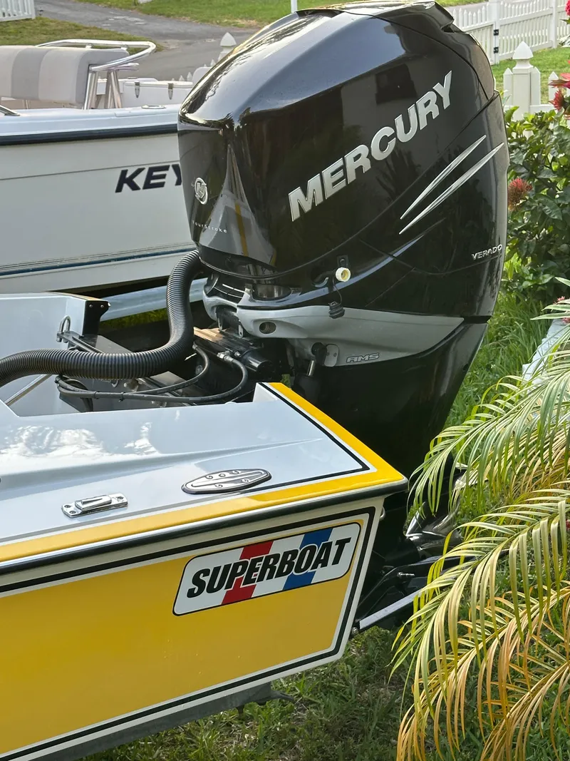 Slide: The Image of 1990 Superboat 21 with Mercury outboard motor, yellow hull, parked near greenery. - 3