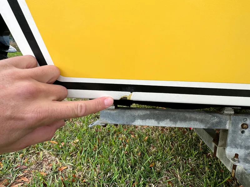 Slide: The Image of Close-up of a 1990 Superboat 21 with a finger pointing at hull damage. - 31