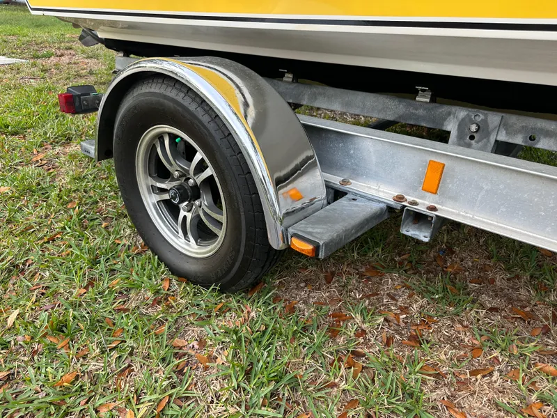 Slide: The Image of Trailer wheel of 1990 Superboat 21 on grass, featuring chrome fender and yellow boat hull. - 33