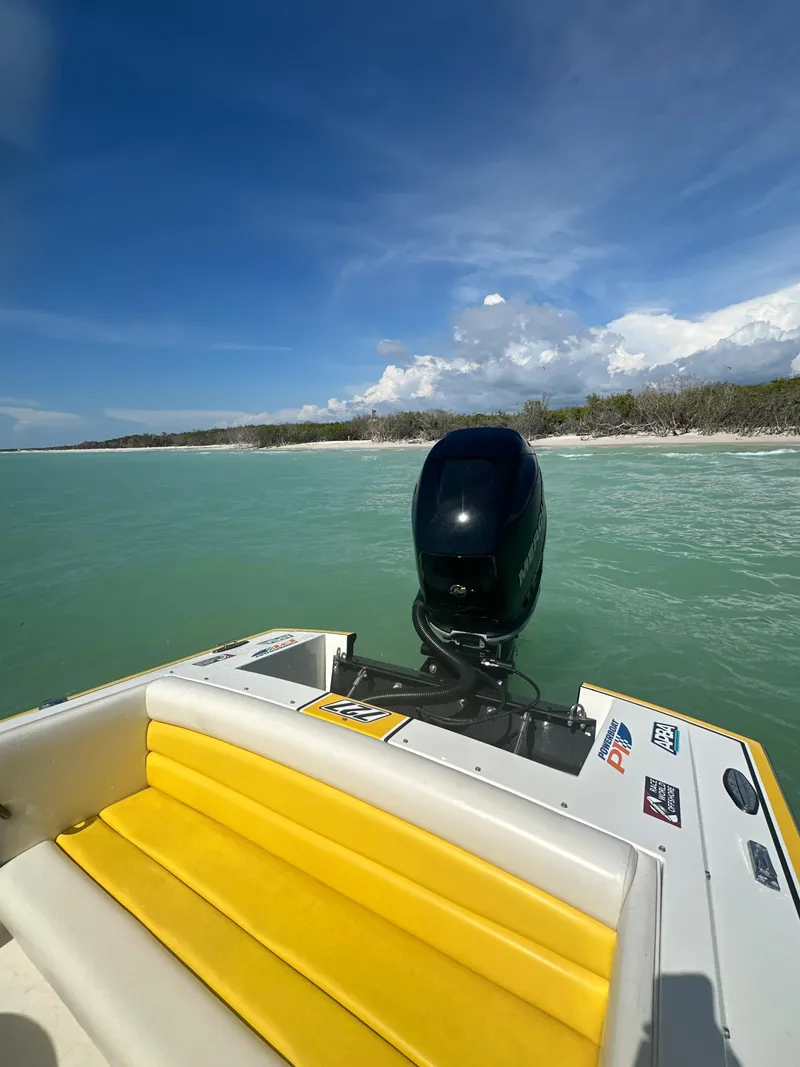 Slide: The Image of 1990 Superboat 21 with yellow seating, cruising on turquoise waters under a clear sky. - 44