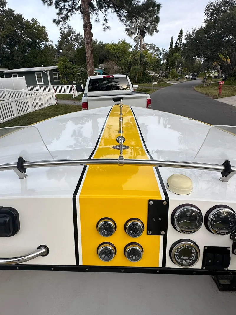 Slide: The Image of 1990 Superboat 21 with yellow stripe, gauges, and parked on a residential street. - 8