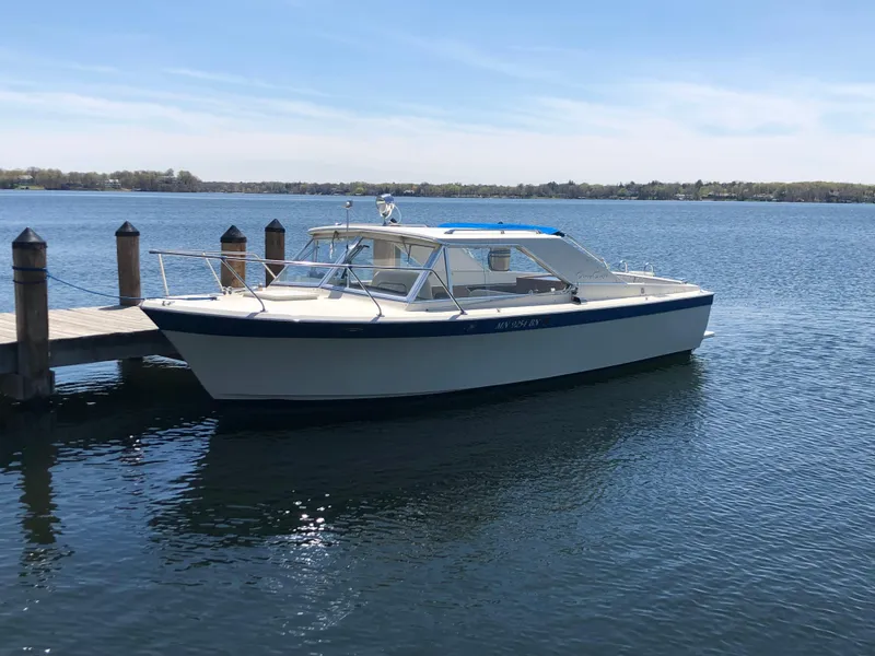 Slide: The Image of 1968 Chris-Craft COMMANDER 27 boat docked on calm water under a clear sky. - 0