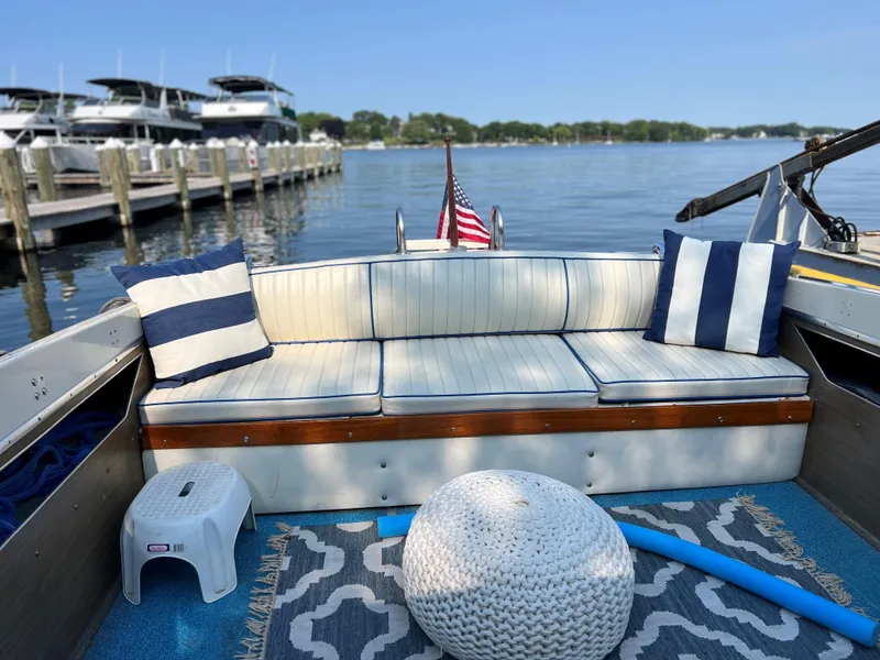 Slide: The Image of 1968 Chris-Craft COMMANDER 27 boat interior with striped cushions, docked by a serene lake. - 19